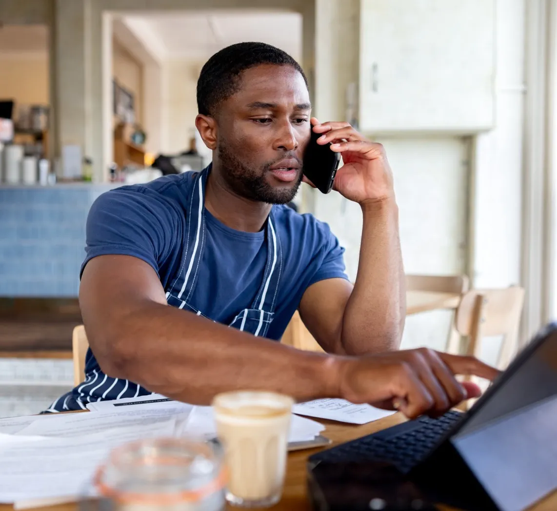 A business owner taking a call while he works at his laptop