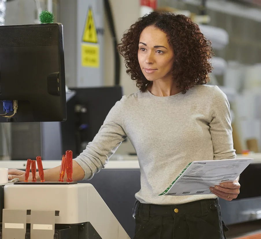 A print shop owner checking an order sheet beside her cutting table
