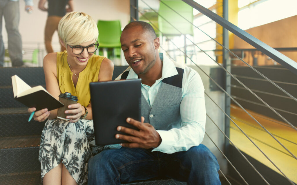 man sitting with a woman, showing her his tablet