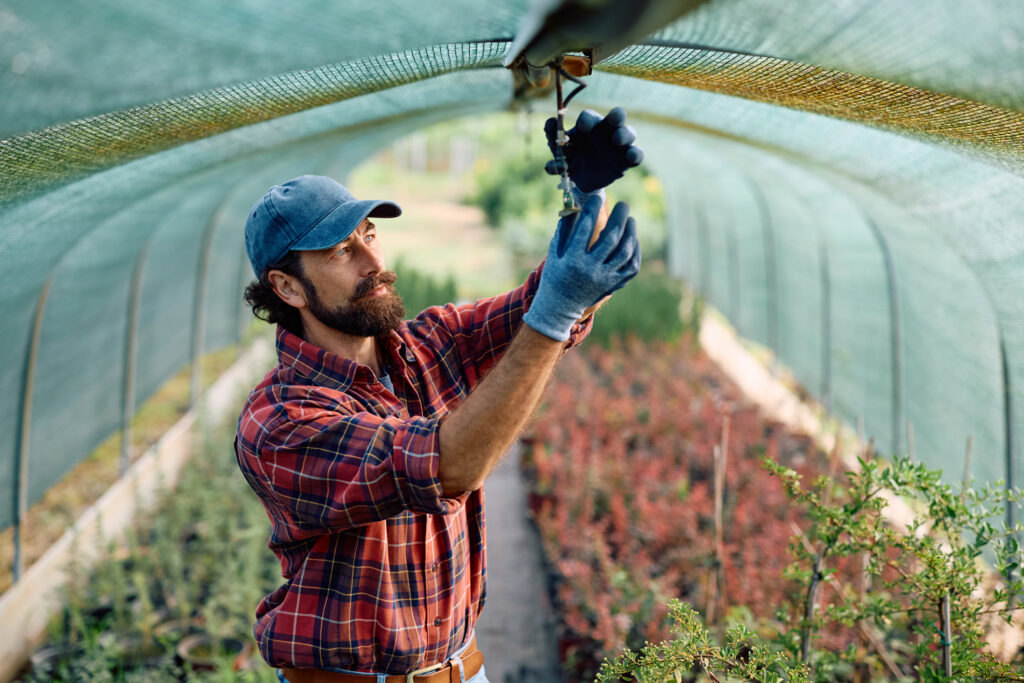Male Entrepreneur setting up the sprinkler at plant nursery.
