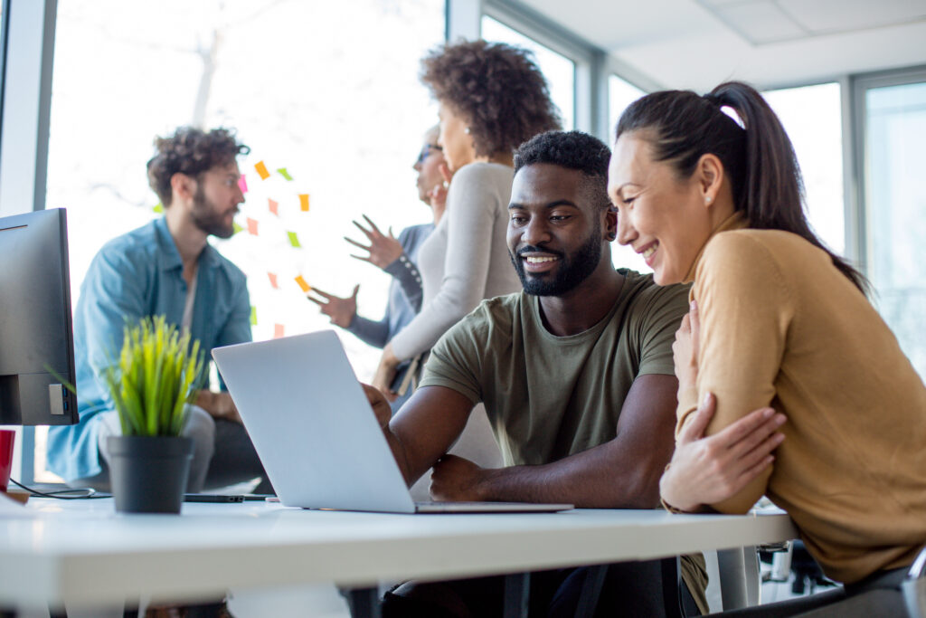 Man and woman sitting down at a computer smiling