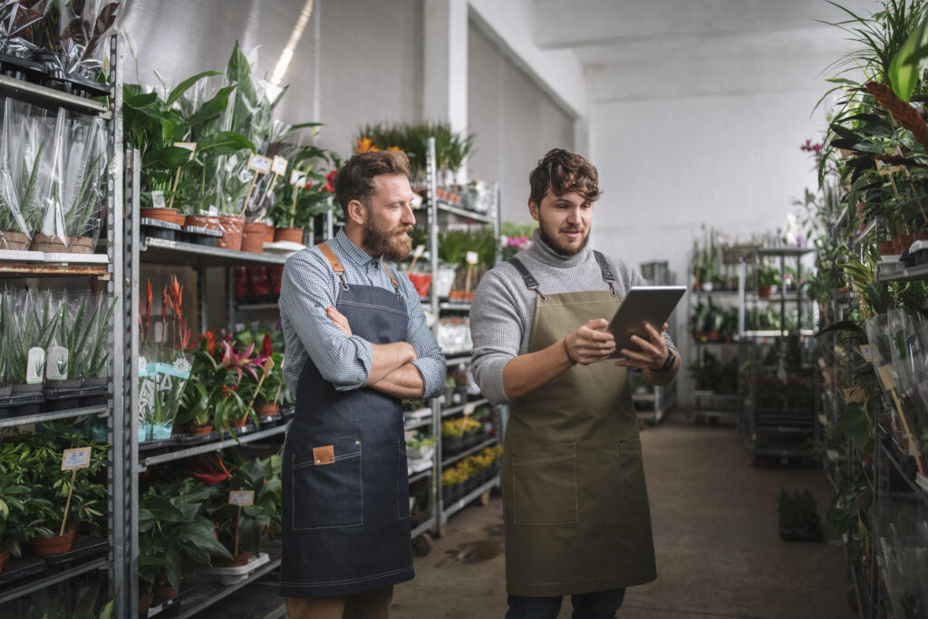 Using Technology In Small Business, Male Workers using digital tablet in flower warehouse.