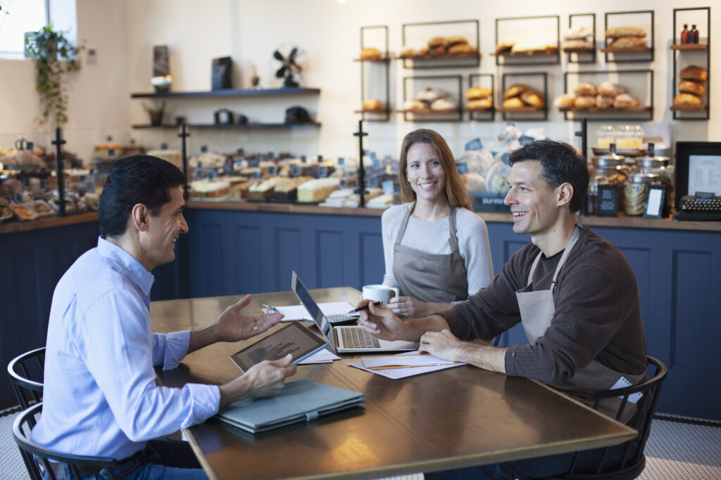 Male investor talking to women and man owners of a bakery cafe