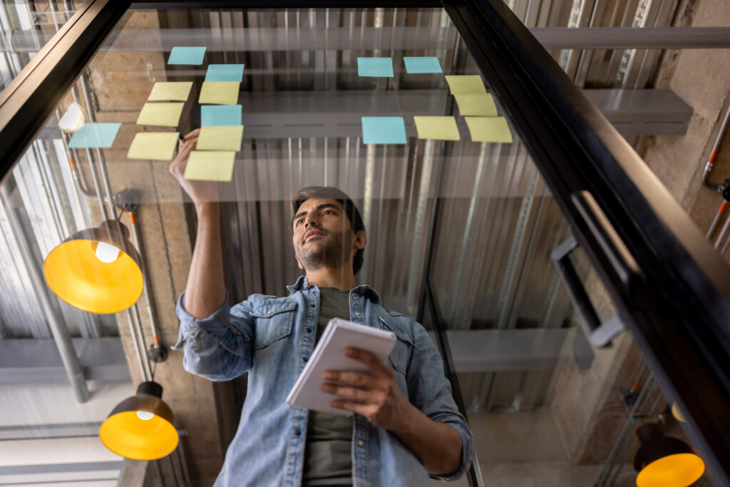 Successful entrepreneur using sticky notes to brainstorm at the office