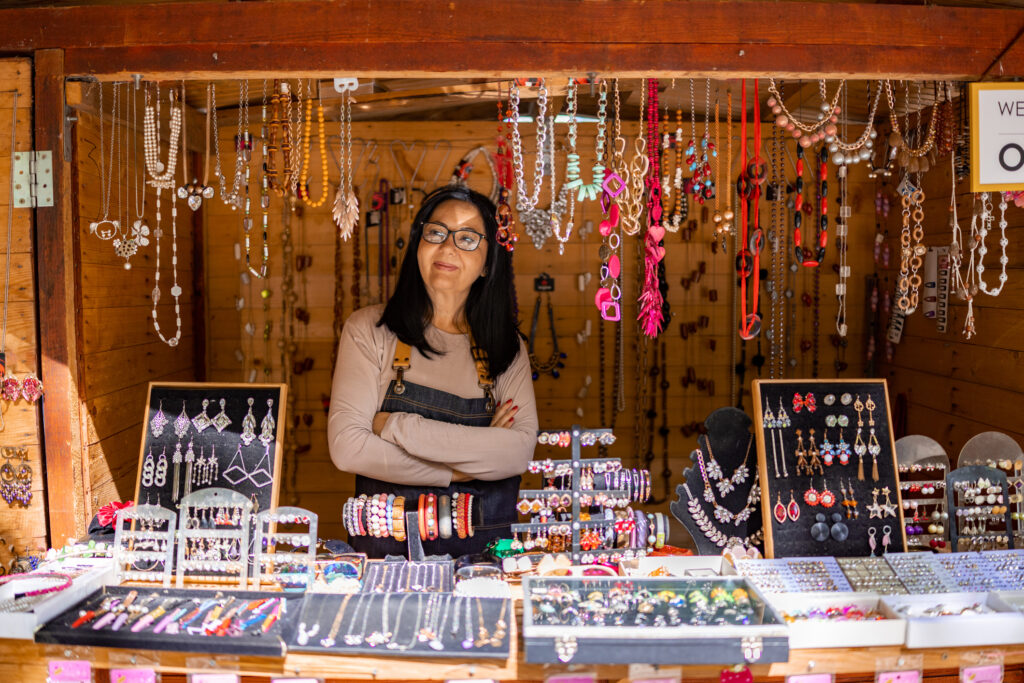 The artisan selling her unique jewelry creations at her cozy street market booth
