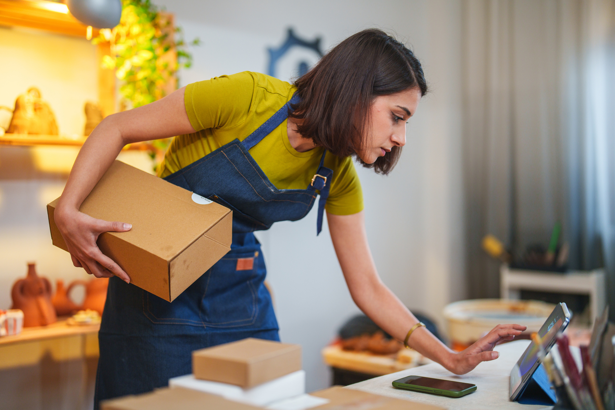 Young female entrepreneur runs an online business from her ceramics studio.