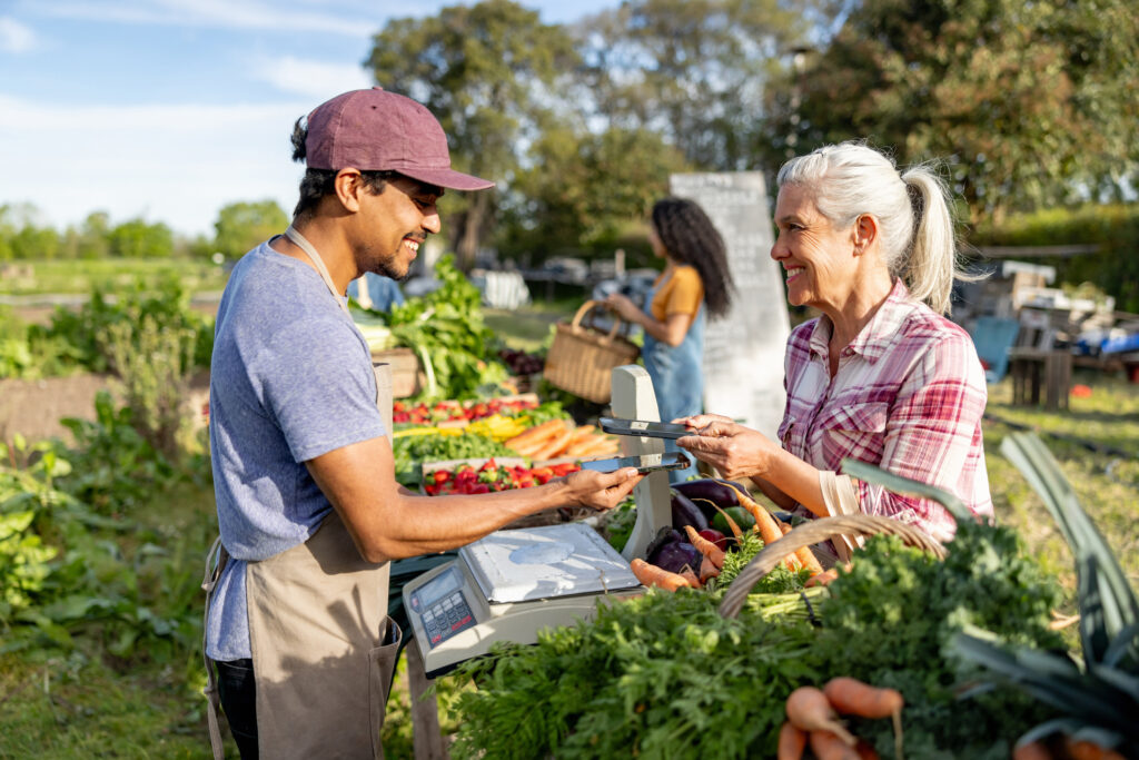 Happy woman making a contactless payment at a Farmer's Market