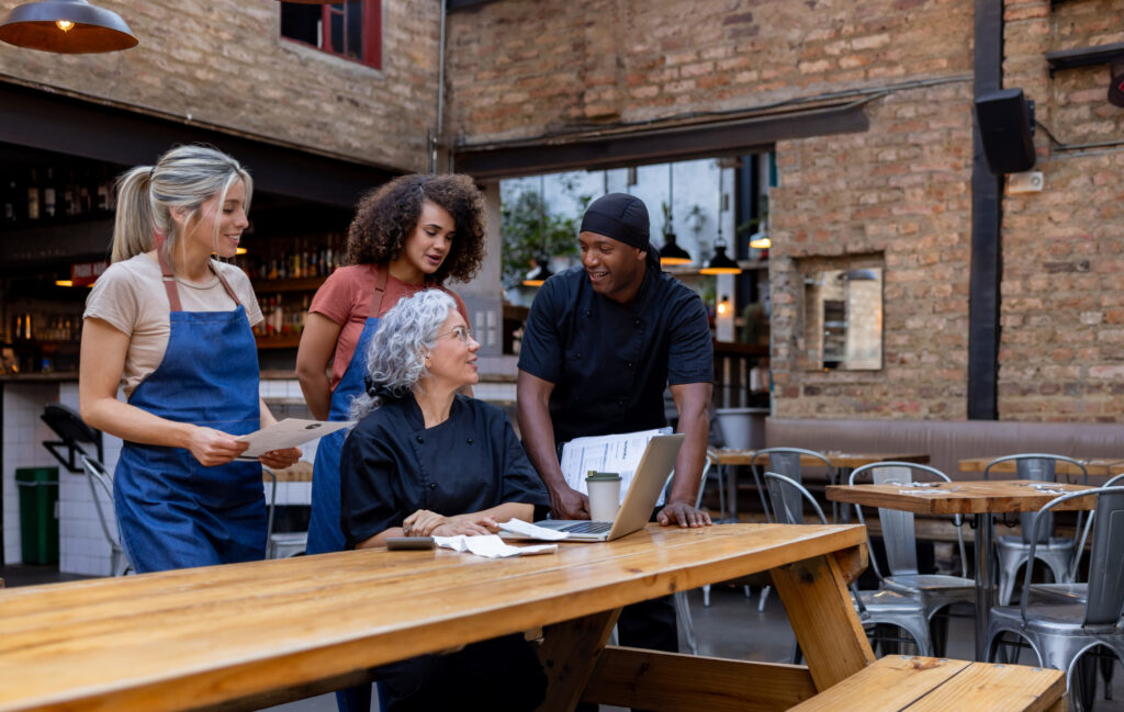 Happy group of restaurant employees doing the accountancy and talking in a staff meeting