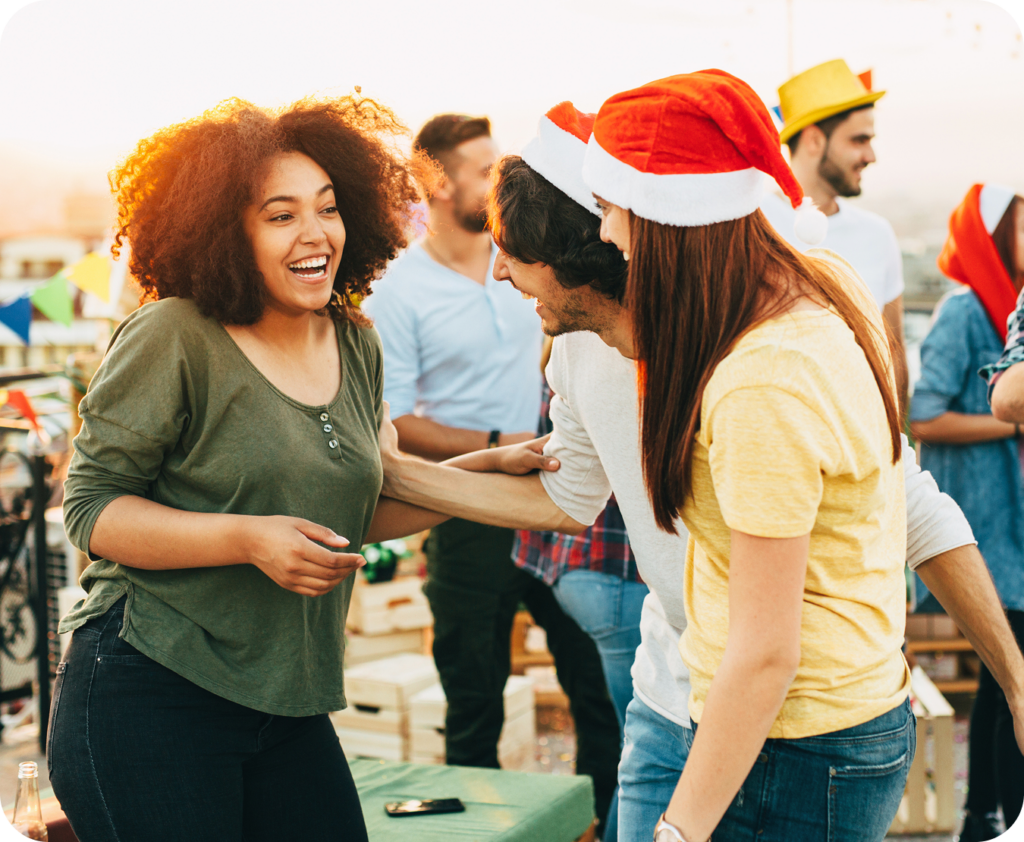 coworkers standing, one is in a santa hat
