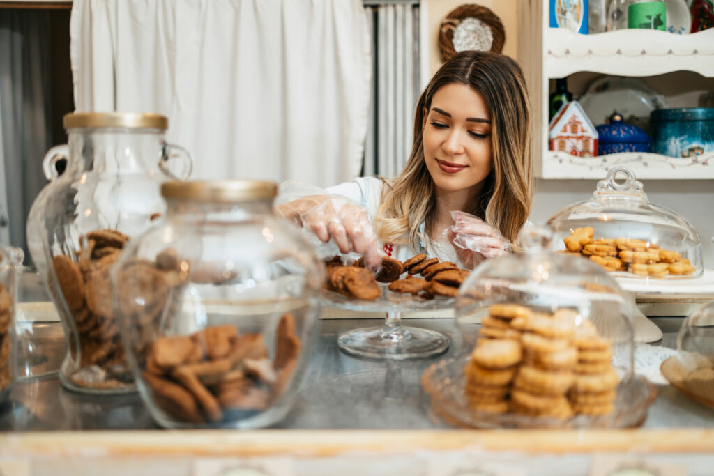 young female working in a bakery, packing delicious sweets.