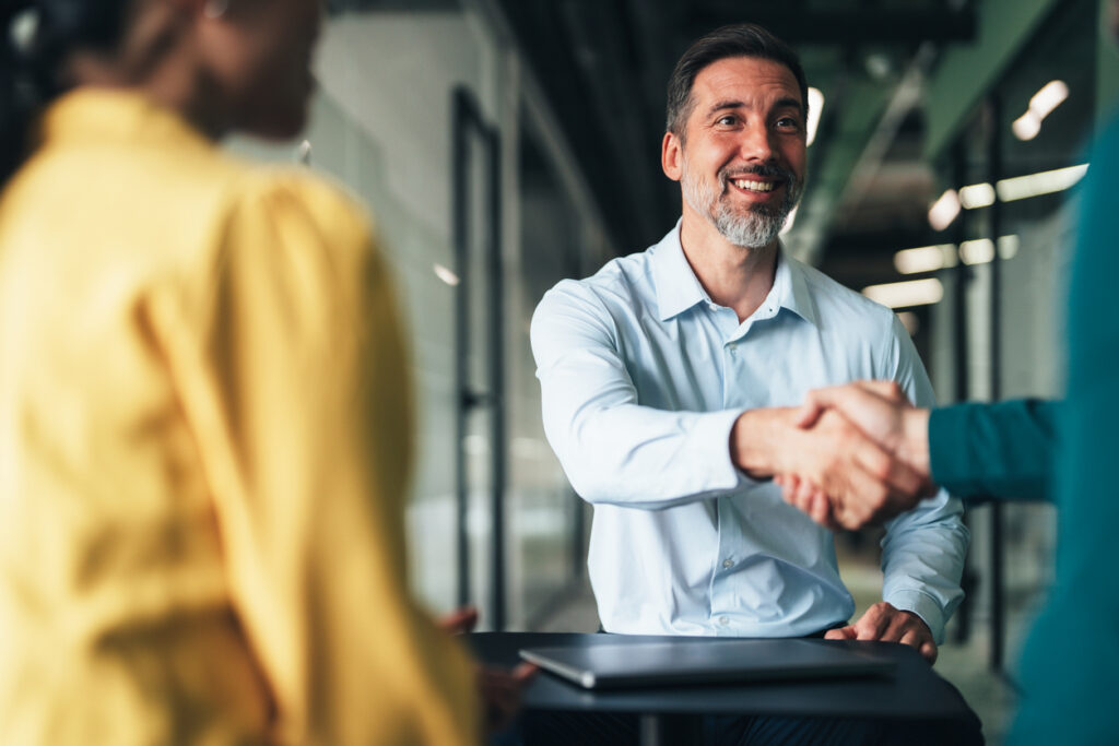 Real estate agent closing property deal with clients sealed with handshake