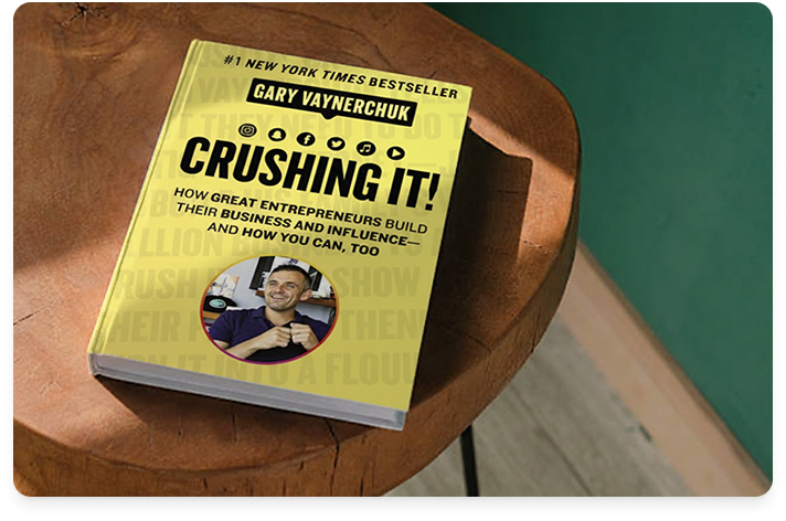 Image of the book Crushing It sitting on a round wood table with a green wall in the background.
