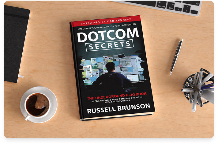 Image of the book Dotcom Secrets on a blonde wood desk near a pen, computer, and coffee cup.