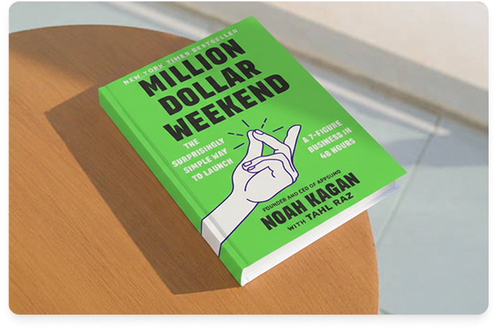 Image of the book Million Dollar Weekend perched at the edge of a round, blonde wood table with a white floor and wall in the background.