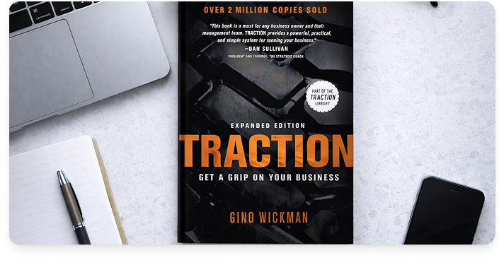 The book Traction by Gino Wickman laying on a white desk.